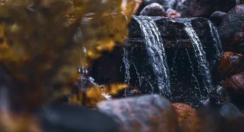 Vesi valuu kivien yli purossa.