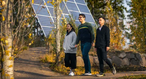 International Technology and Engineering Science students walk in front of solar panel.