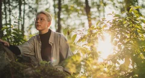 LUT University master's student in a forest at sunset