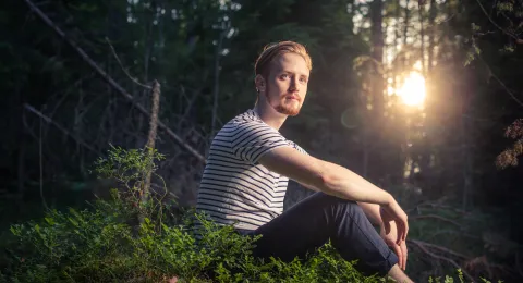 LUT University student sitting in a forest at sunset 