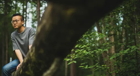 LUT University student in a forest sitting on a tree branch