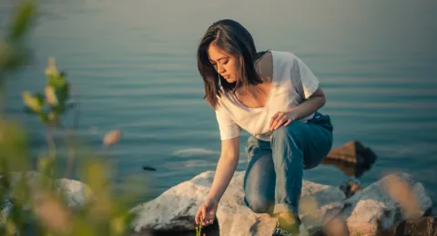 LUT University student examining plant at shore