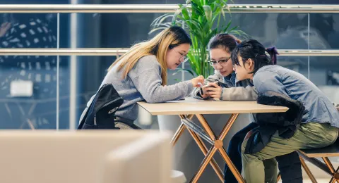 LUT students checking phone in campus cafeteria.