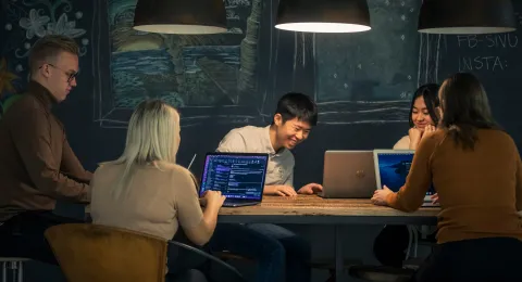 Iloisia opiskelijoita tietokoneiden ääressä.