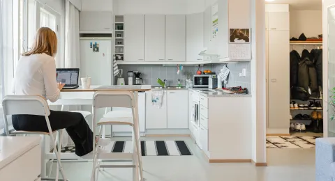 Opiskelija istuu keittiössä tietokoneen ääressä.