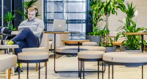 Opiskelija istuu tietokone sylissään.