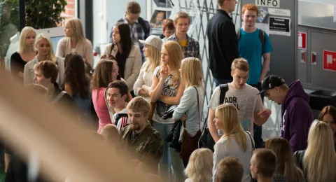 Opiskelijoita seisomassa yliopiston aulassa.