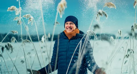 A happy person standing in snow during winter 