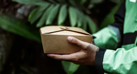 a cardboard food package on human&#039;s hand