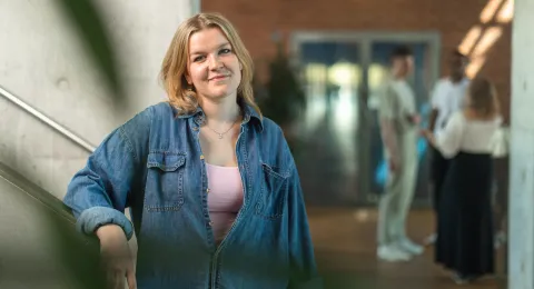 Opiskelijoita kauppakorkeakoulun tiloissa, joista yksi katsoo kameraan ja hymyilee.