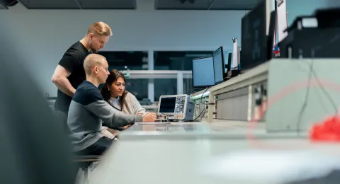 Kolme ihmistä katsoo tietokoneen ruutua laboratoriossa.