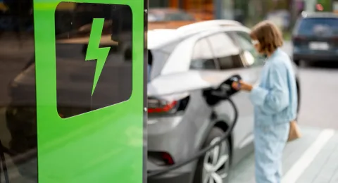 Nainen lataamassa sähköautoa, woman charging an electric car