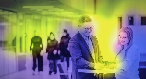 Henkilöt keskustelemassa puhelin kädessään pöydän ääressä. 