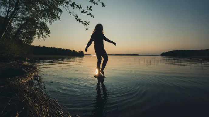 LUT University student balancing on a rock above water 