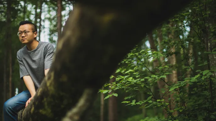 LUT University student in a forest sitting on a tree branch