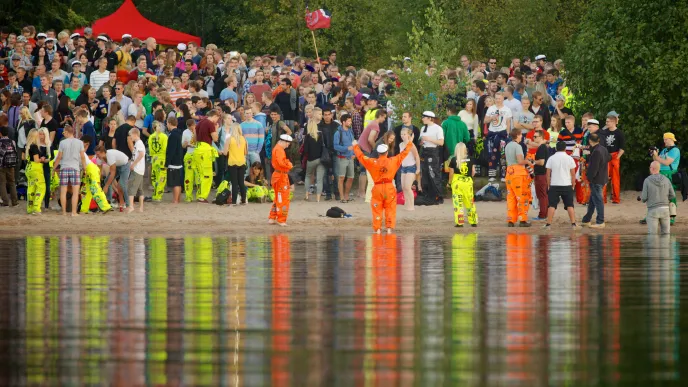 Students partying on beach of lake Saimaa at LUT University in overalls