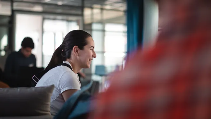 People sitting in a room, a woman smiling