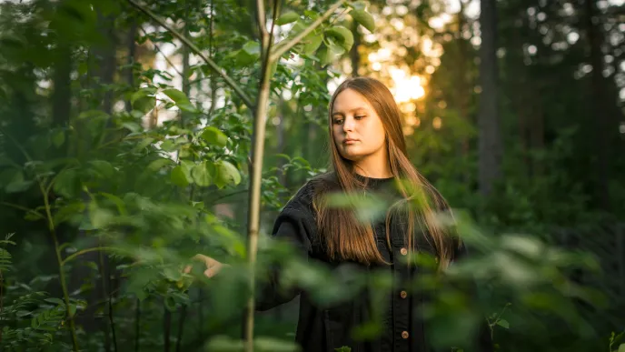 Henkilö seisoo metsässä.