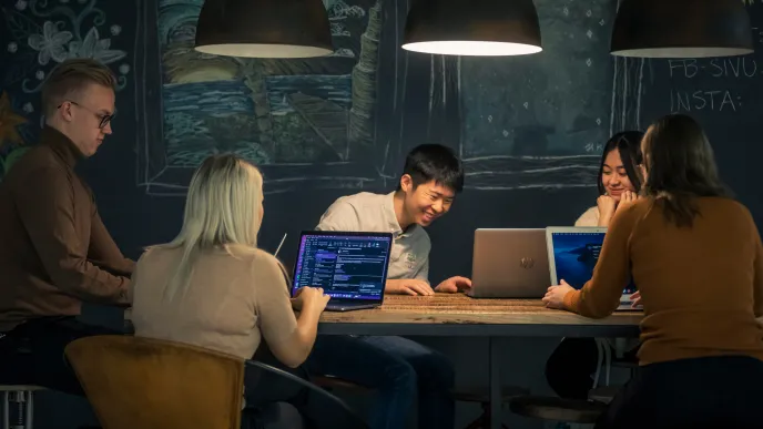 Iloisia opiskelijoita tietokoneiden ääressä.