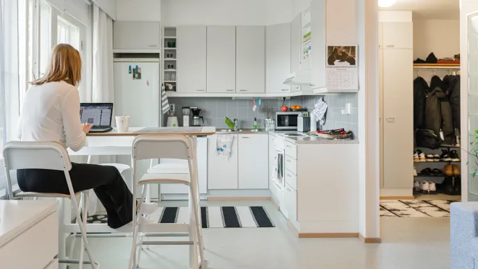 Opiskelija istuu keittiössä tietokoneen ääressä.