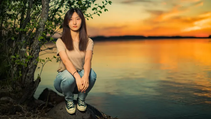 Opiskelija rannalla auringonlaskussa.