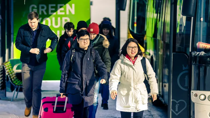 Two students arriving with suitcases on campus