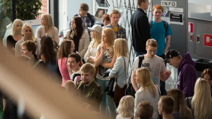 Opiskelijoita seisomassa yliopiston aulassa.