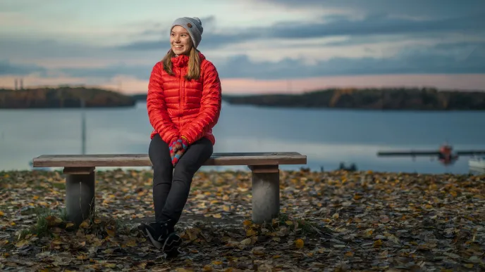 Opiskelija istumassa järven rannalla