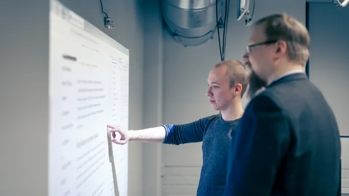 Opiskelija ja opettaja tietotekniikan käytettävyyslaboratoriossa.