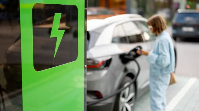 Nainen lataamassa sähköautoa, woman charging an electric car