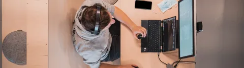 Henkilö koodaa tietokoneella