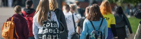 Uusia opiskelijoita ja tuutori kävelemässä yliopiston pihalla.