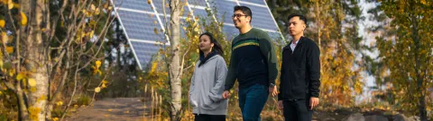 Opiskelijoita kävelemässä aurinkopaneelin ohi.