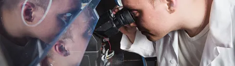 Opiskelija katsoo mikroskoopin läpi