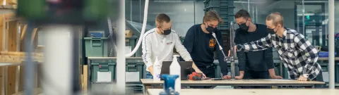 Konetekniikan opiskelijoita pöydän ääressä.