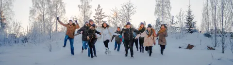Opiskelijoita juoksemassa kameraa kohti talvisessa maisemassa.