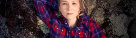 Henkilö makaa kiven päällä ja katsoo ylös haaveillen.