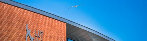 LUT University Lappeenranta Campus from outside with a seagull flying on the sky