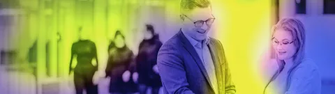 Henkilöt keskustelemassa puhelin kädessään pöydän ääressä. 
