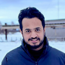 Mustafa is smiling into the camera with a snowy background.